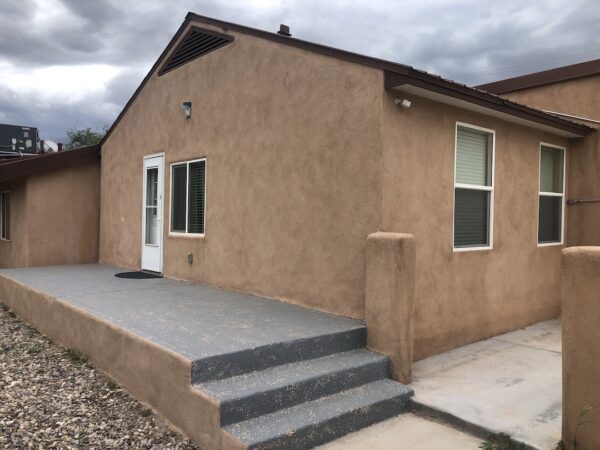 Alamo Apartment A Exterior of adobe building with gravel yard