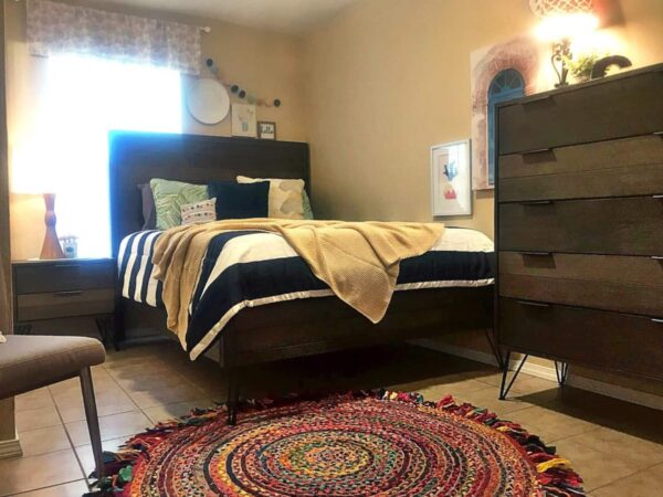 Alamo Apartment C dark wood bedroom with striped comforter and colorful rug