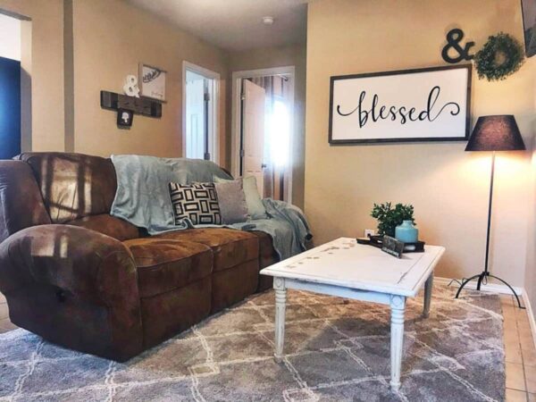 Alamo Apartment D living area with brown suede sofa and farm style coffee table